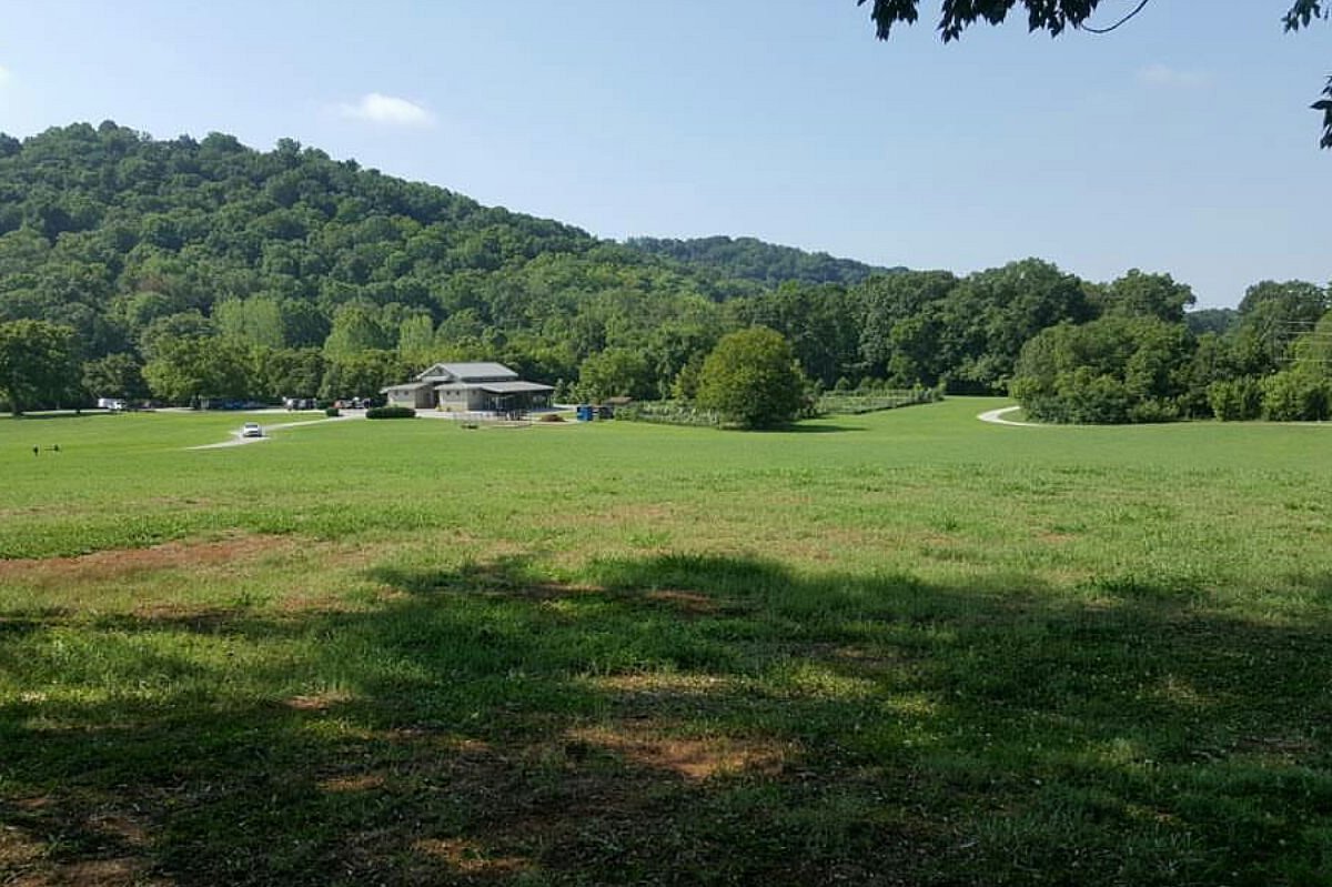A view of Greenway Farms landscape with grassy land and mountains with a barn showcasing a perfect place for an outdoor activity.